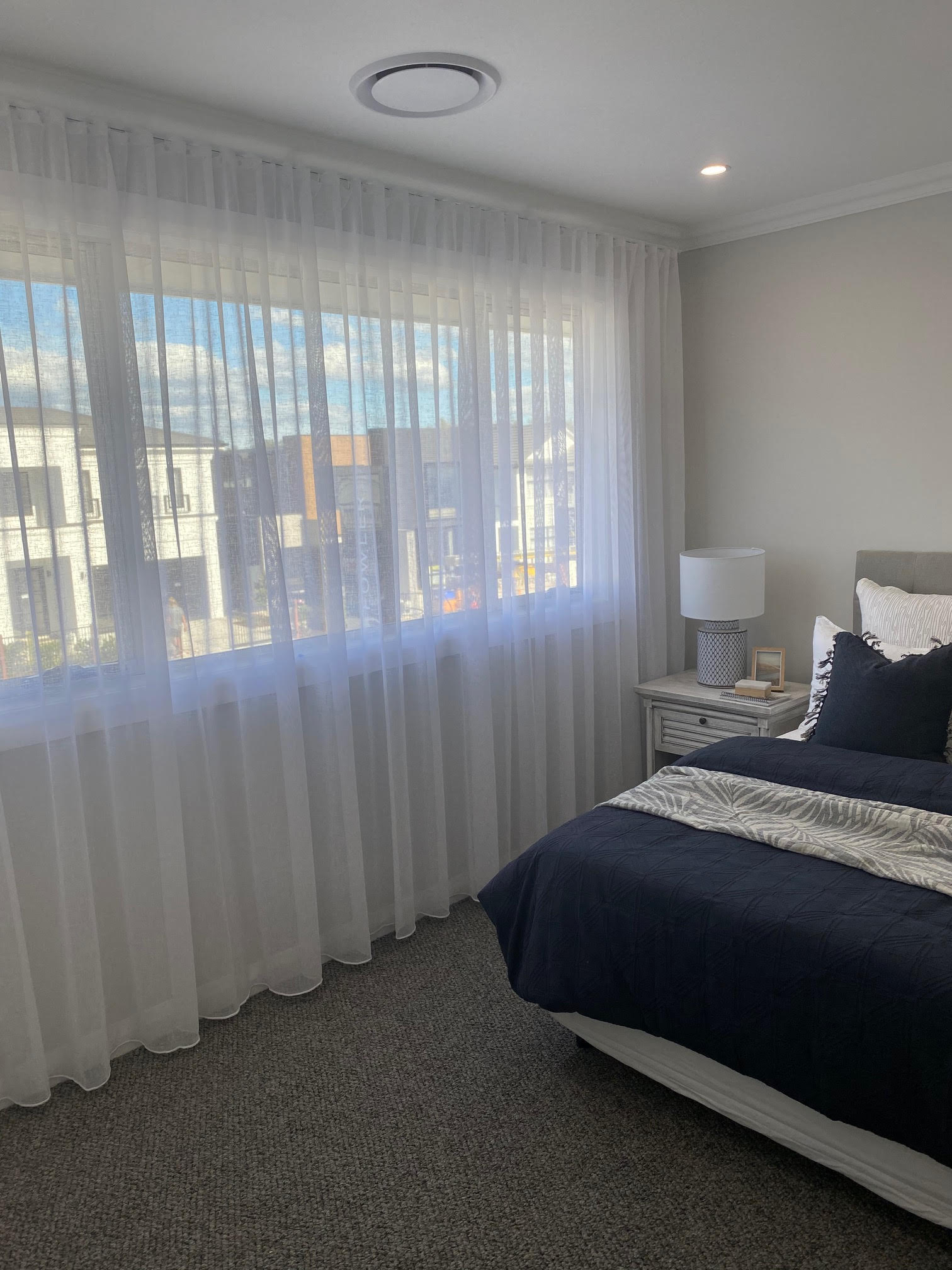 White sheer curtains in a bedroom with navy bedding